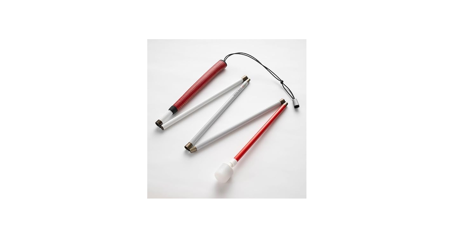 An Ambutech NO-JAB folding white cane folded flat in a zigzag: white sections joined by the elastic cord that runs through them, a deep red grip at the handle end trailing a thin black wrist loop, a red lower section, and a white marshmallow tip at the very end.