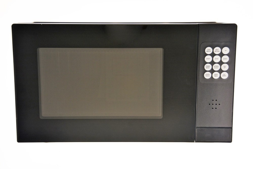 A black talking microwave oven: a large dark mesh door window takes up the left two-thirds, and on the right a control panel of twelve big round white raised buttons arranged in a grid — cook minutes, seconds, start, stop, power reset, kitchen timer, clock, and volume among them — with a small speaker grille of punched holes below the buttons.